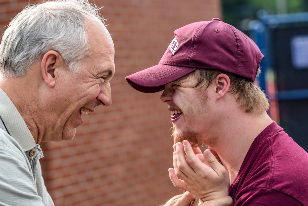A young man and an older adult laughing together.